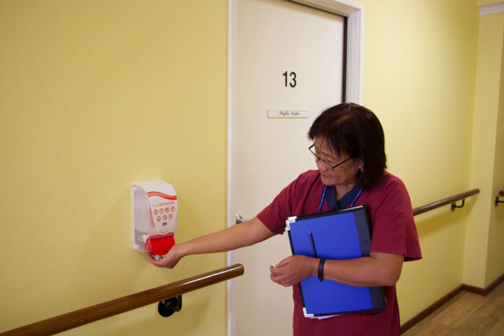 Jamie sanitising her hands outside a door